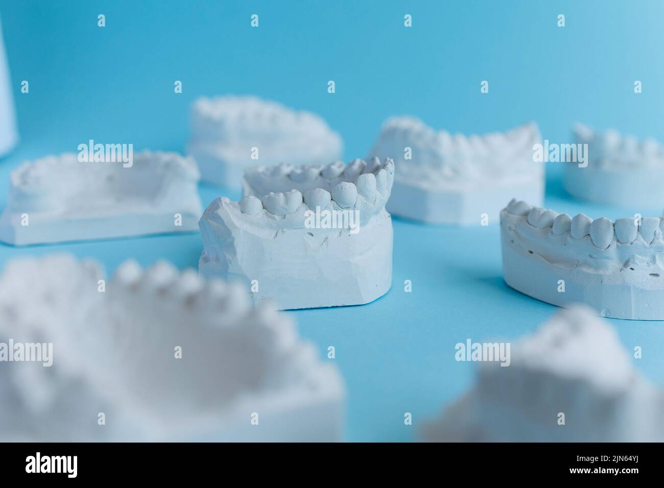 Molti modelli di denti in gesso su sfondo blu Foto Stock