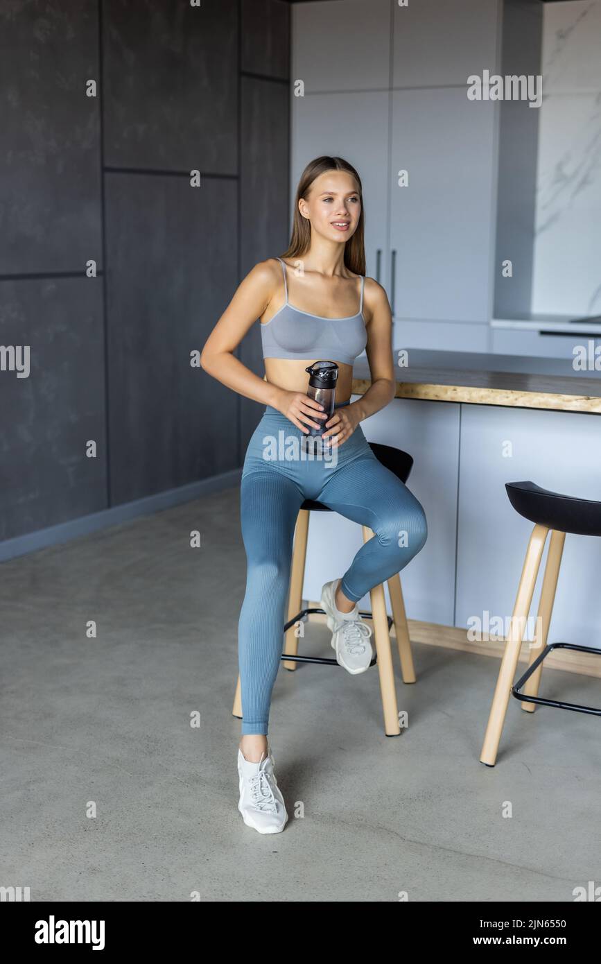 Mantenere idratato. Giovane donna in forma che beve acqua sul tappeto yoga a casa Foto Stock