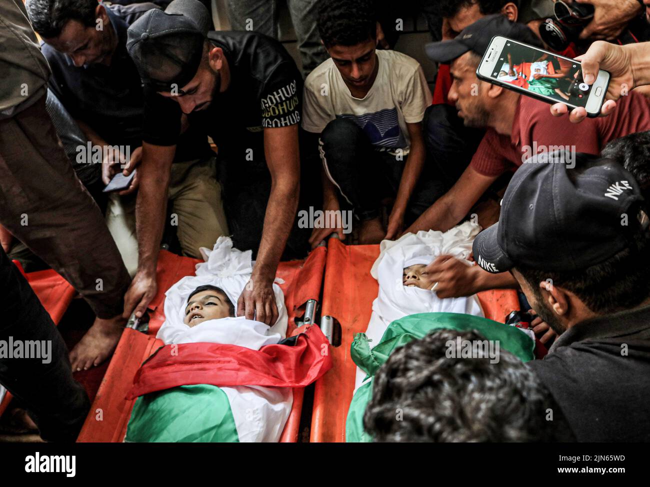 Gaza, Palestina. 08th ago 2022. (NOTA DEI REDATTORI: L'immagine raffigura la morte) i parenti di Yasser al Nabahin e dei suoi tre figli si siedono accanto ai loro corpi durante il funerale, uccisi in un attacco aereo israeliano sul campo profughi di Bureij nella striscia centrale di Gaza. Il cessate il fuoco ha posto fine a 3 giorni di violenza tra la Jihad islamica e Israele, iniziata venerdì quando Israele ha ucciso i leader della sua ala militare per la Jihad islamica, Tayseer al-Jabari e Khaled Mansour nella striscia di Gaza. (Foto di Yousef Masoud/SOPA Images/Sipa USA) Credit: Sipa USA/Alamy Live News Foto Stock