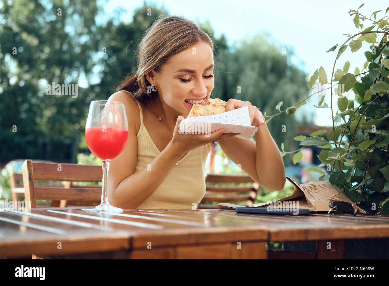 La giovane donna cotta una sottile frittella ripiena di funghi, prosciutto e formaggio seduti sulla terrazza all'aperto Foto Stock