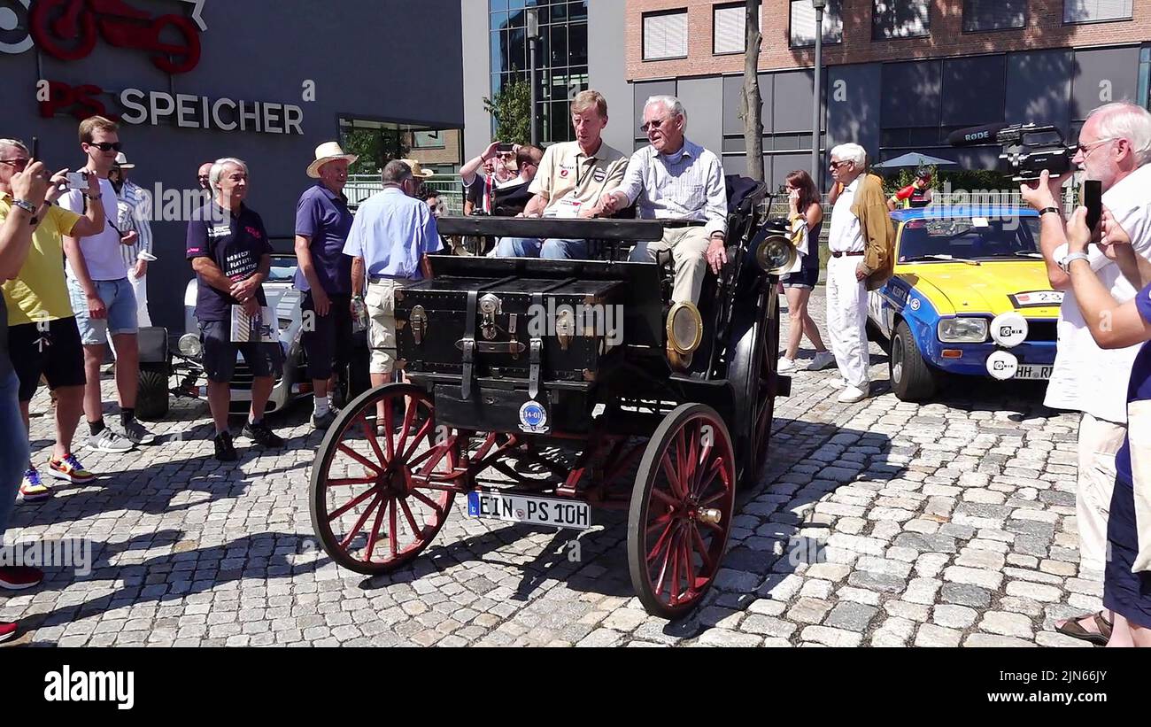 09 agosto 2022, bassa Sassonia, Einbeck: Ex campione del mondo di rally Walter Röhrl (l) prende una lezione di guida dal collettore di auto e moto Karl-Heinz Rehkopf sulla più vecchia automobile registrata del mondo, un Benz Victoria No. 99 costruito nel 1894 (ancora dal video dpa). Röhrl fermato dalla PS Speicher con il Rally Olimpico '72 Revival 2022 con oltre 200 vetture classiche, che corre da Kiel a Monaco e ricrea il Rally Olimpico 1972, e ha preso la lezione di guida speciale. Foto: Julian Stratenschulte/dpa Foto Stock