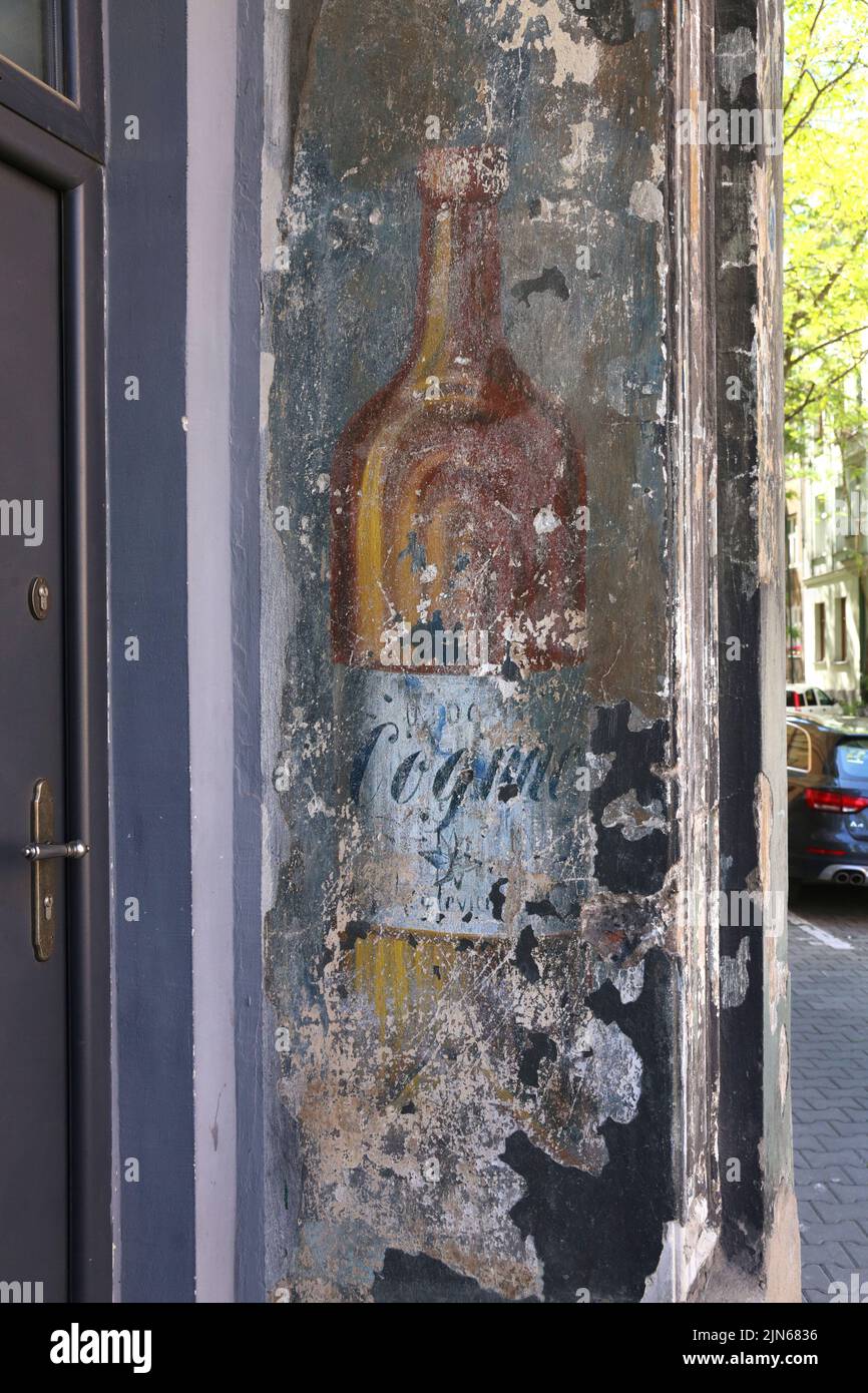 Cracovia. Cracovia. Polonia. Bottiglia di cognac, un vecchio esterno vintage parete dipinta annuncio di ex ristorante. Foto Stock