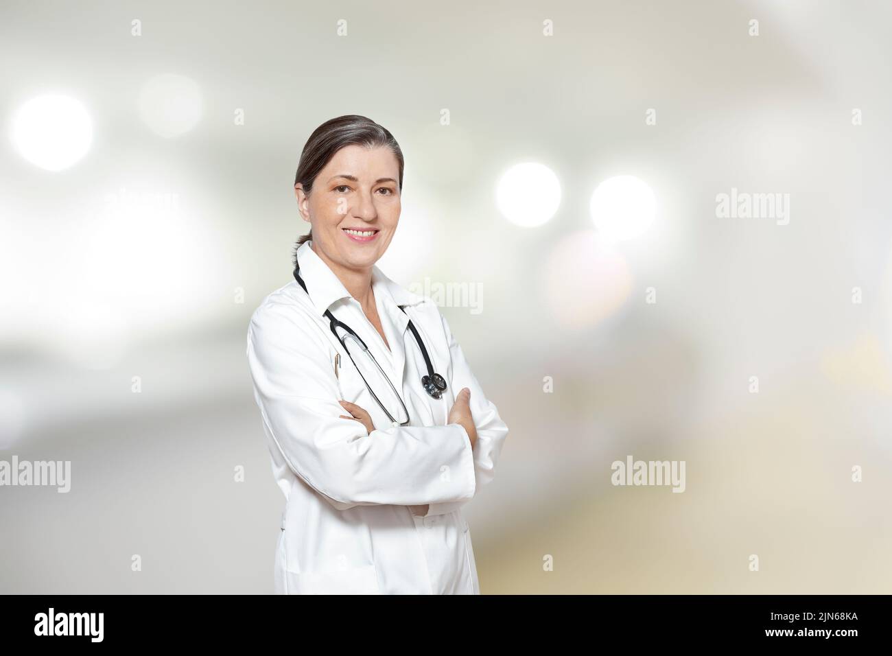 Medico di mezza età in un camice bianco da laboratorio, sorridente amichevole, nella sua pratica o chirurgia, copia o spazio di testo. Foto Stock