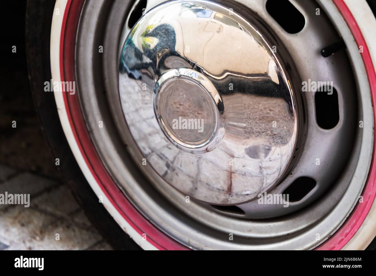 Ruota auto vintage con cappuccio cromato e striscia rossa, primo piano Foto Stock