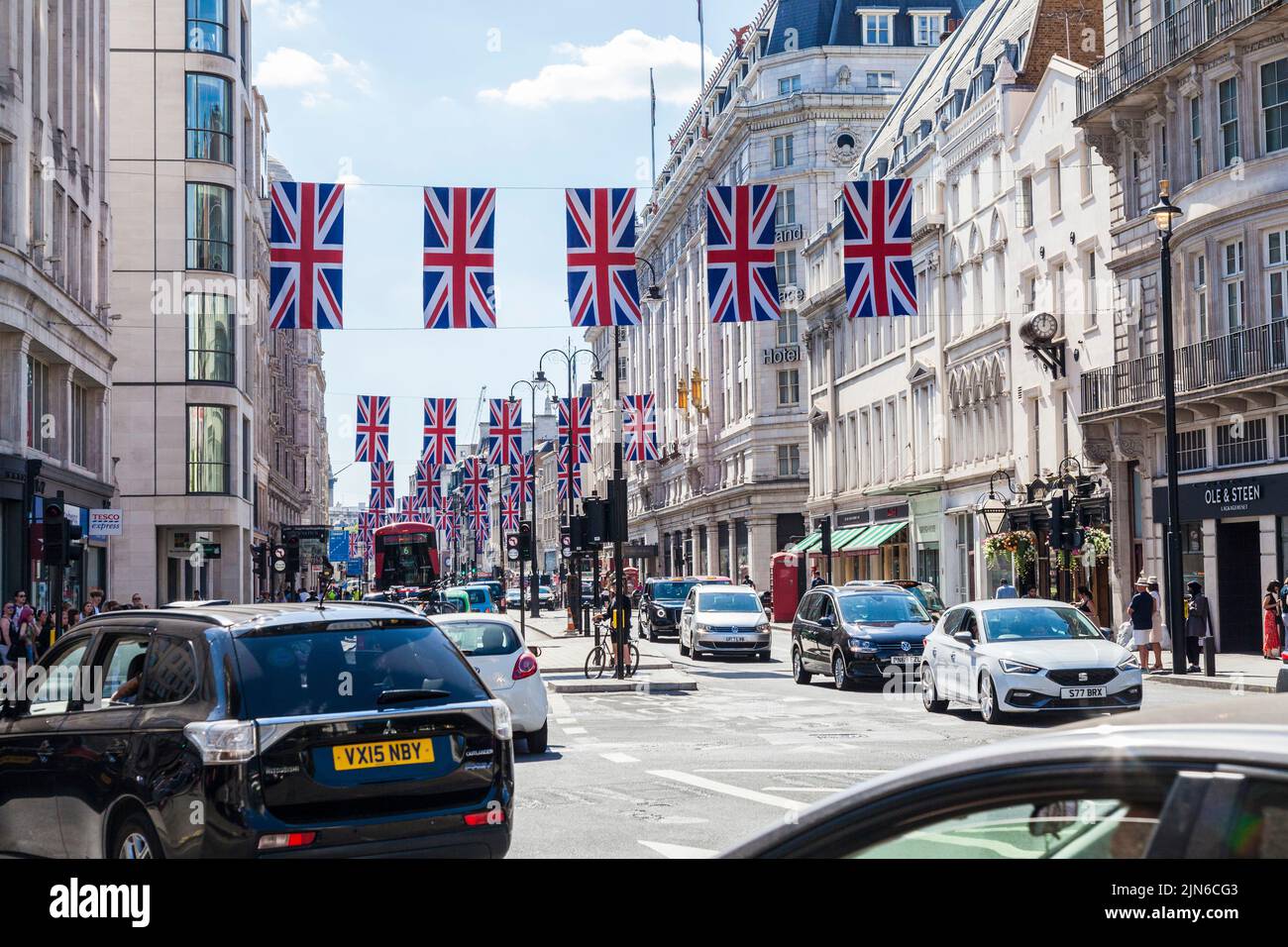 Una scena di strada nel West End di Londra, Inghilterra, Regno Unito con le bandiere di Union Jack drappeggiato dall'altra parte della strada Foto Stock