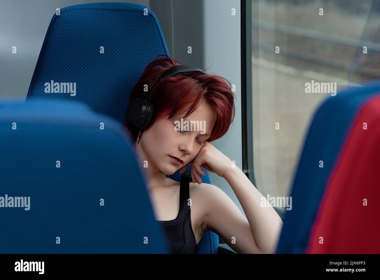 la giovane donna si è tolta seduta su una sedia in un treno suburbano Foto Stock