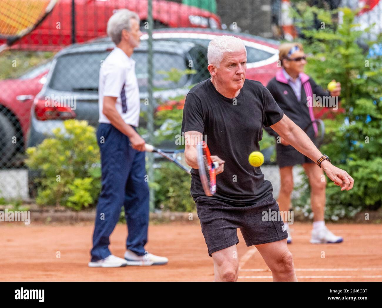 Persone di mezza età e anziane che imparano a giocare a tennis Foto Stock