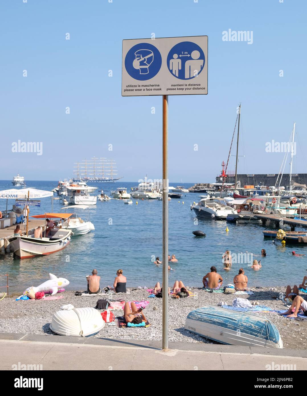 Informazioni sul Covid cartelli segnaletici sul lungomare del villaggio di Positano in Italia con spiaggia e lungomare sullo sfondo.Social distanze e maschere. Foto Stock