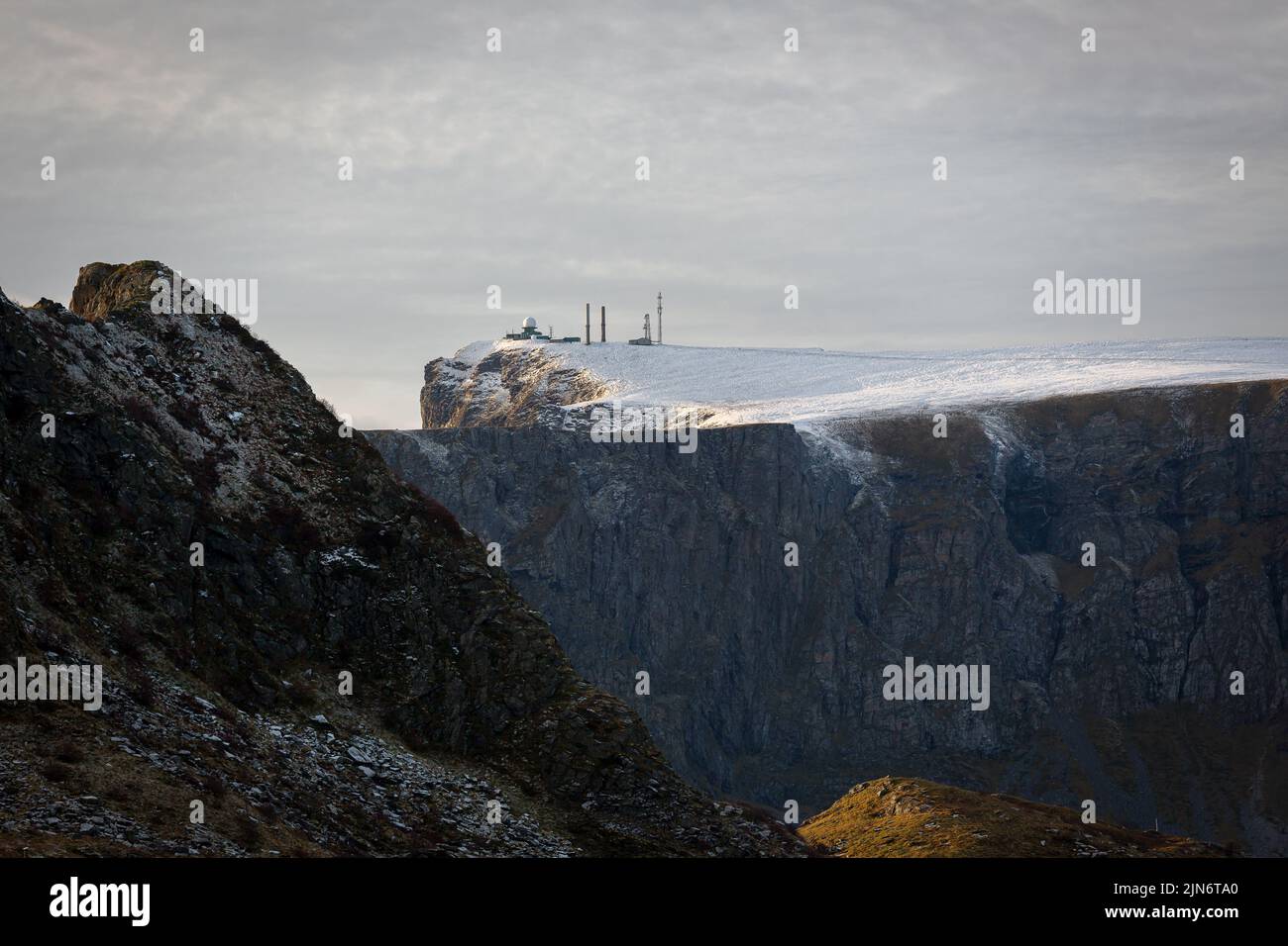 La vista di un edificio stazione meteo sulla scogliera innevata e una cima di una montagna Foto Stock