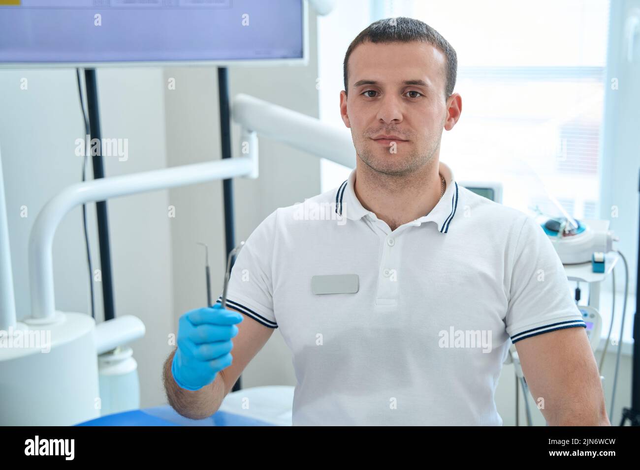 Dentista maschile professionista che mostra gli strumenti diagnostici per l'esame della cavità orale Foto Stock