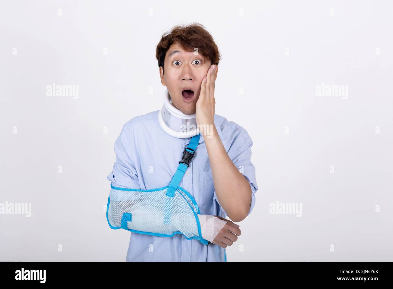 Ritratto di uomo asiatico con braccio rotto e collo sensazione di sorpresa e scioccato isolato su sfondo bianco copia spazio Foto Stock