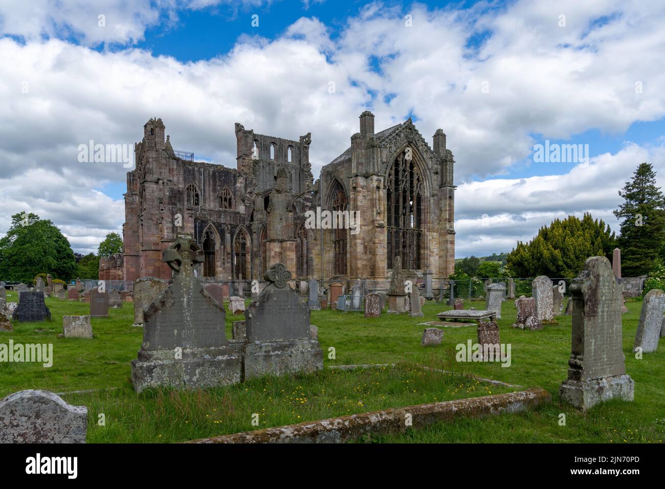 Melrose, Regno Unito - 19 Giugno, 2022: Vista delle rovine dell'abbazia di Melrose e delle pietre storiche nel cimitero della chiesa Foto Stock