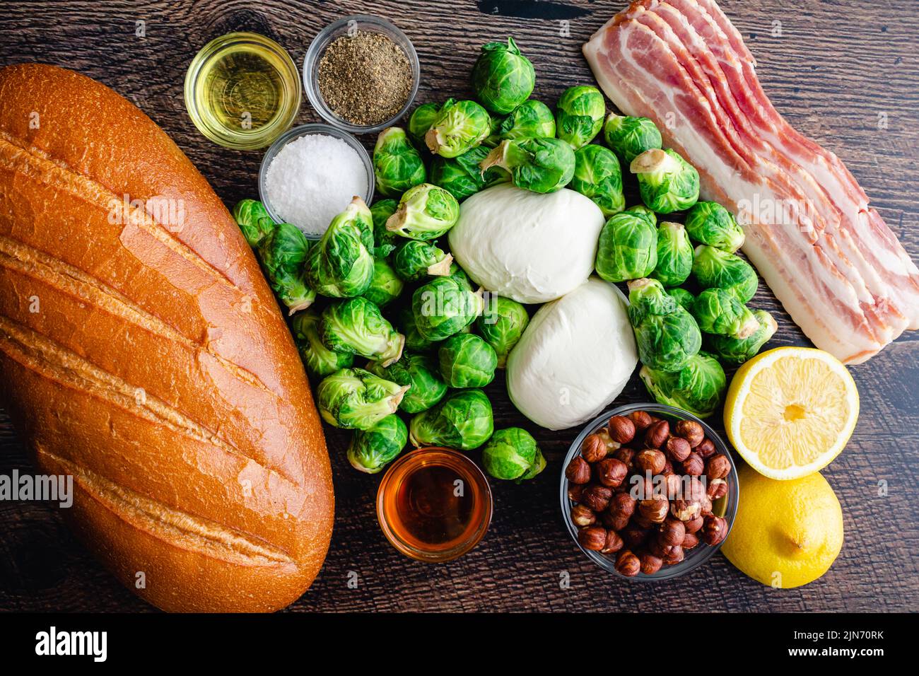 Brussels Sprout toast caramellato con Burrata & Bacon ingredienti: Pane fresco, germogli di Bruxelles e altri ingredienti su sfondo di legno Foto Stock