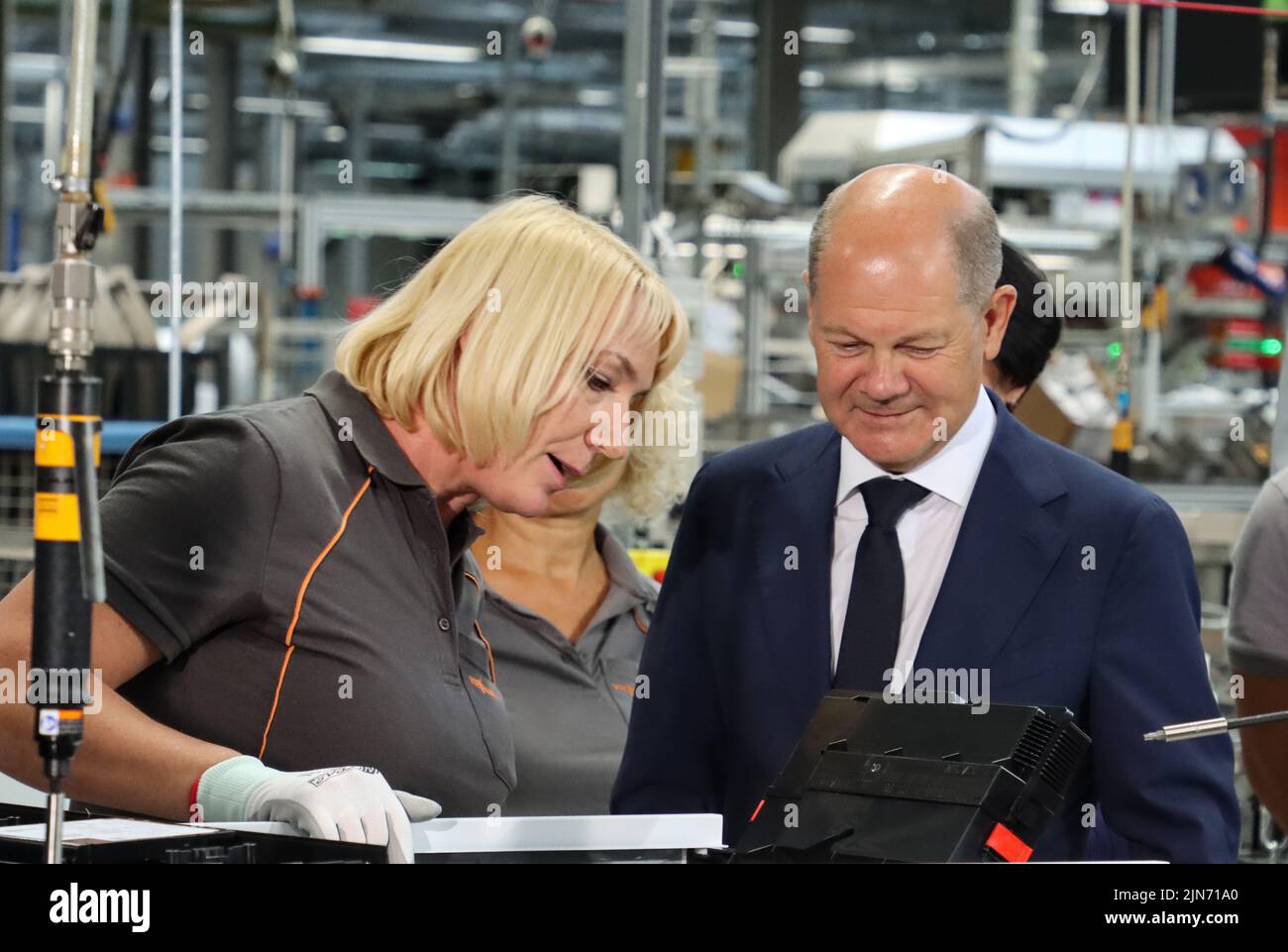 23 maggio 2022, Hessen, Allendorf (Eder): Il cancelliere tedesco OLAF Scholz (SPD) avvita l'ultima vite in una pompa di calore sotto la guida di un dipendente Viessmann. Scholz ha appreso informazioni sulle pompe di calore e sulle soluzioni per il clima verde presso l'azienda a conduzione familiare Viessmann. Foto: Nadine Weigel/dpa Foto Stock