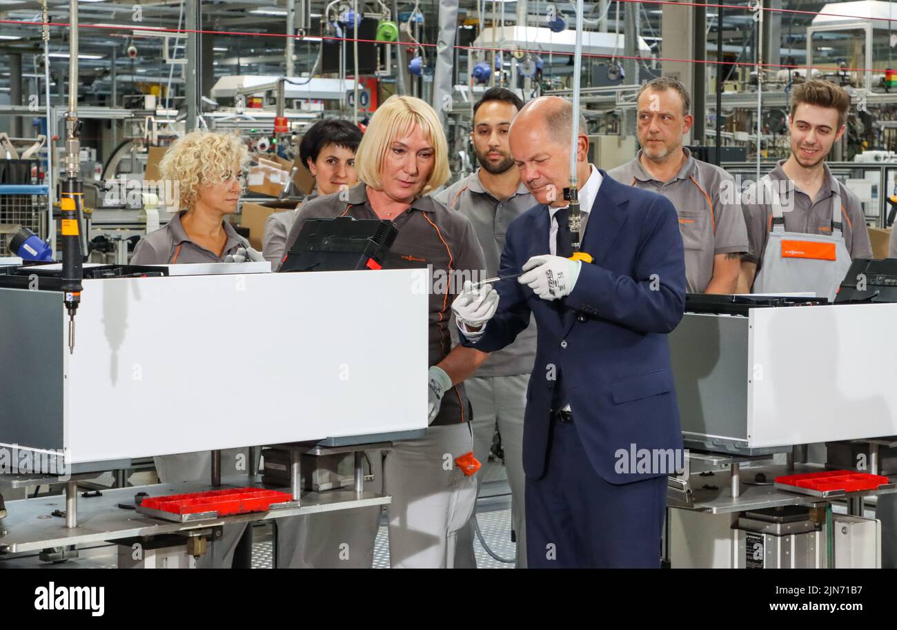 23 maggio 2022, Hessen, Allendorf (Eder): Il cancelliere tedesco OLAF Scholz (SPD) avvita l'ultima vite in una pompa di calore sotto la guida di un dipendente Viessmann. Scholz ha appreso informazioni sulle pompe di calore e sulle soluzioni per il clima verde presso l'azienda a conduzione familiare Viessmann. Foto: Nadine Weigel/dpa Foto Stock