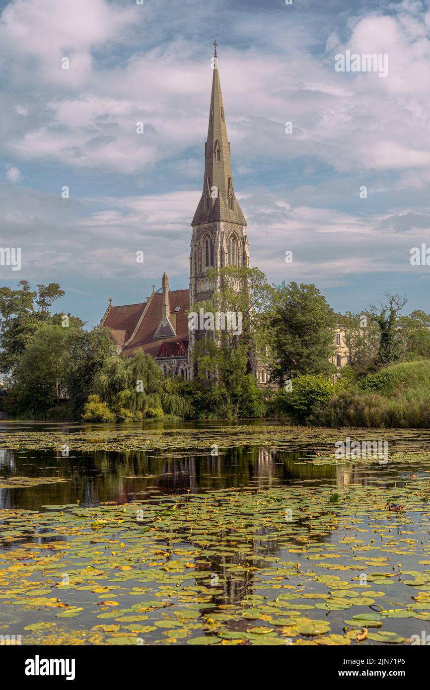 Una foto verticale della chiesa di San Albano a Copenaghen circondata da verde e da uno stagno Foto Stock