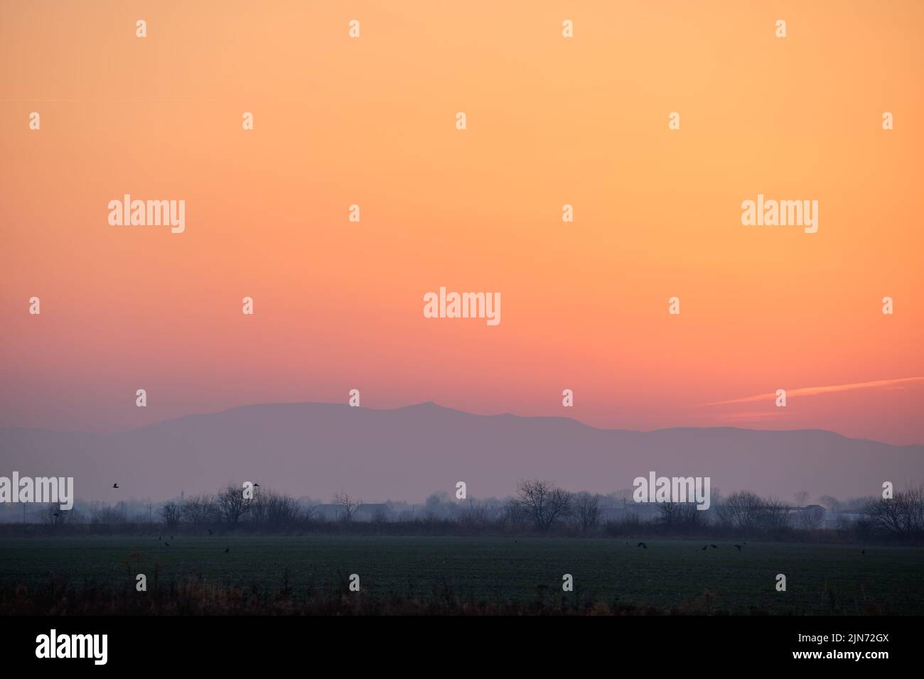 Bellissimo paesaggio panoramico serale con sole luminoso sulle cime lontane al tramonto Foto Stock