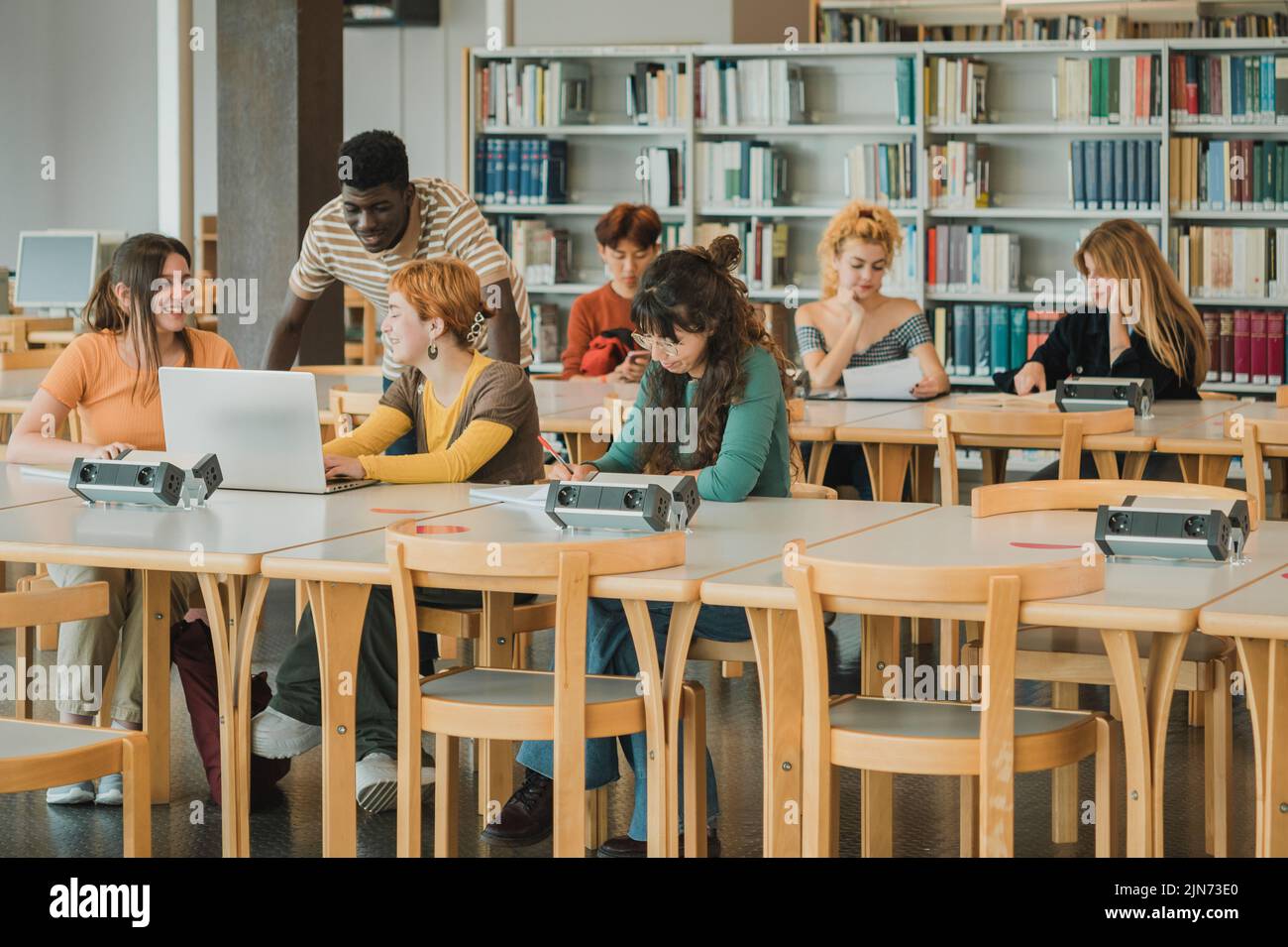 Studenti multietnici che fanno i compiti nella moderna biblioteca Foto Stock