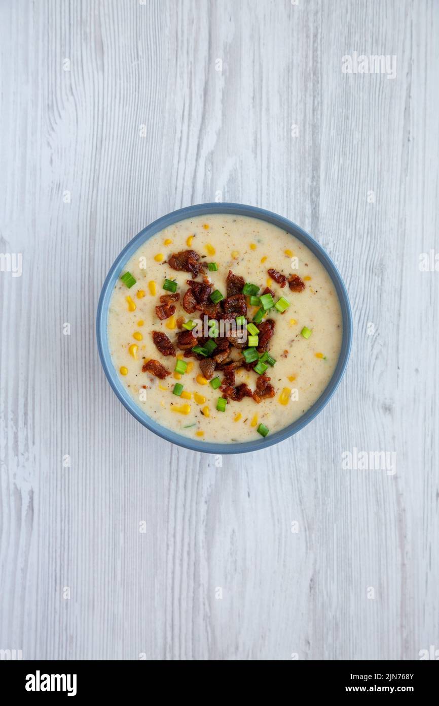 Zuppa di mais fatta in casa con bacon in una ciotola su sfondo bianco in legno, vista dall'alto. Disposizione piatta, sovratesta, dall'alto. Foto Stock