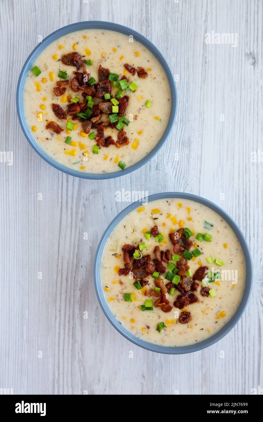 Zuppa di mais fatta in casa con bacon in una ciotola su sfondo bianco in legno, vista dall'alto. Disposizione piatta, sovratesta, dall'alto. Foto Stock