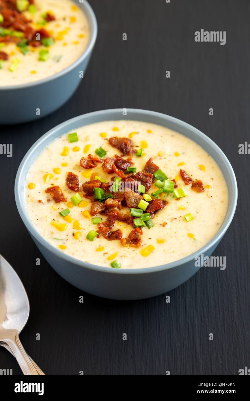 Chowder di mais fatto in casa con bacon in una ciotola su sfondo nero, vista laterale. Foto Stock