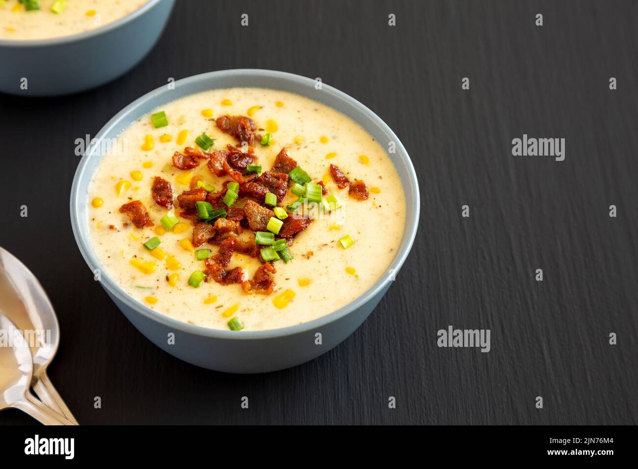 Chowder di mais fatto in casa con bacon in una ciotola su sfondo nero, vista laterale. Spazio di copia. Foto Stock