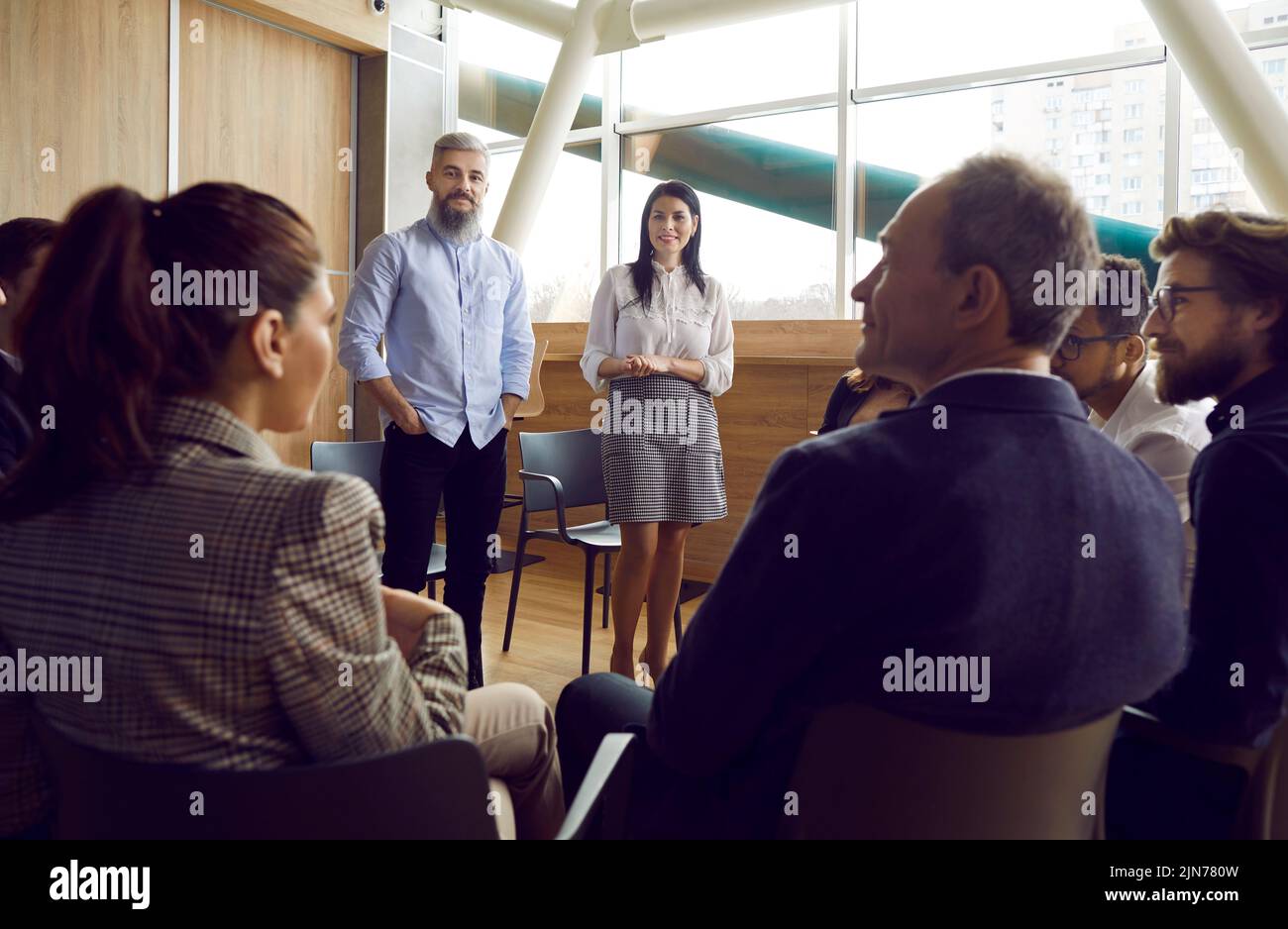 I dirigenti maschi e femmine comunicano con il personale seduto intorno a loro in cerchio sulle sedie. Foto Stock