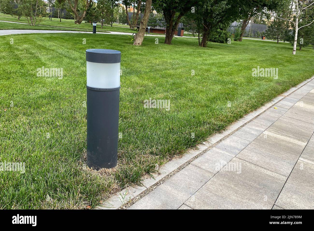 percorso in marmo di piastrelle quadrate, lanterna montata su un prato verde nel parco, luce naturale. spazio copia. Foto Stock