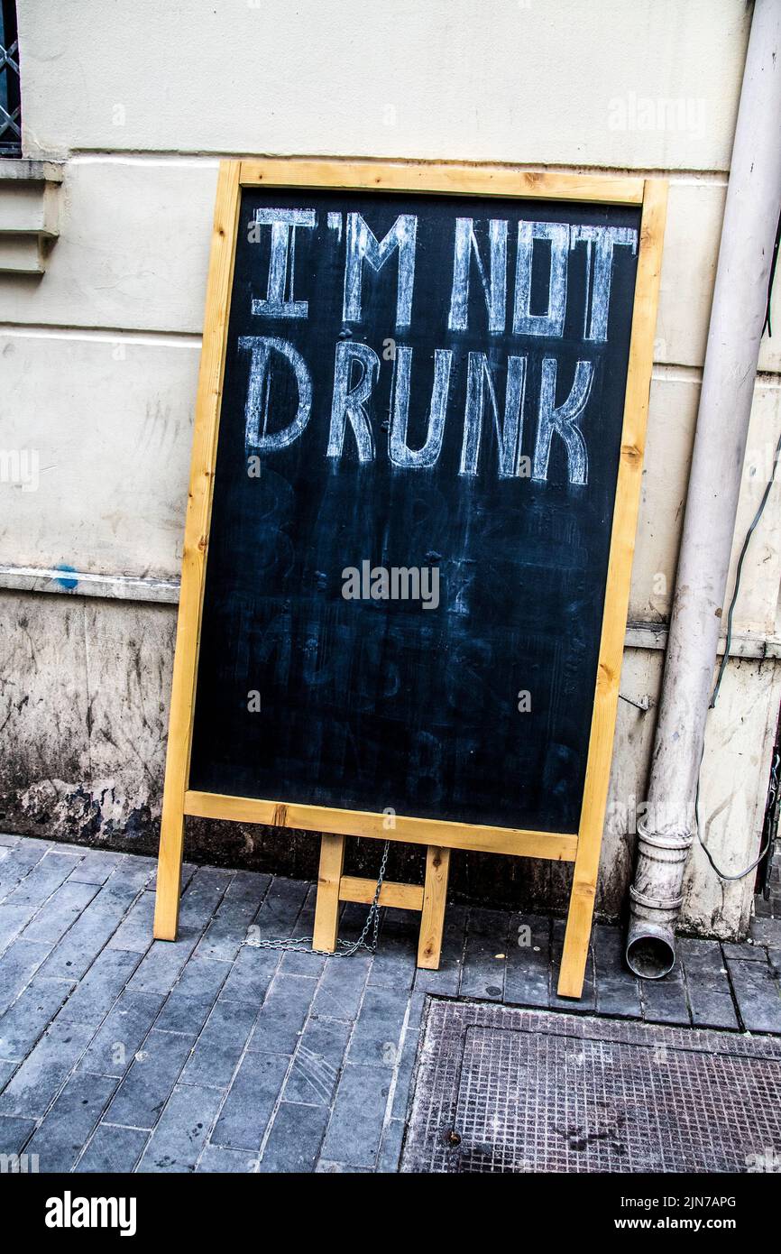 Alzarsi in piedi cartello cartellone pieghevole appeso contro parete grungy e drenaggio da marciapiede con im non ubriaco scritto ordinatamente su di esso con gesso. Foto Stock