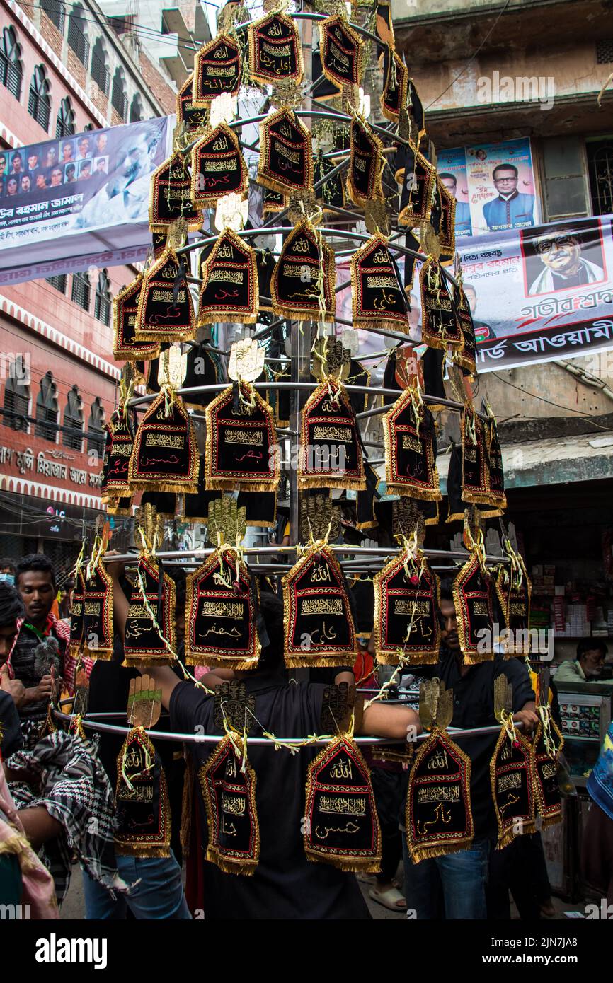 I musulmani sciiti del Bangladesh marciano e portano le bandiere e Tazia durante una processione di Muharram sulla strada principale a Dhaka, Bangladesh, il 09th agosto 2022. Foto Stock