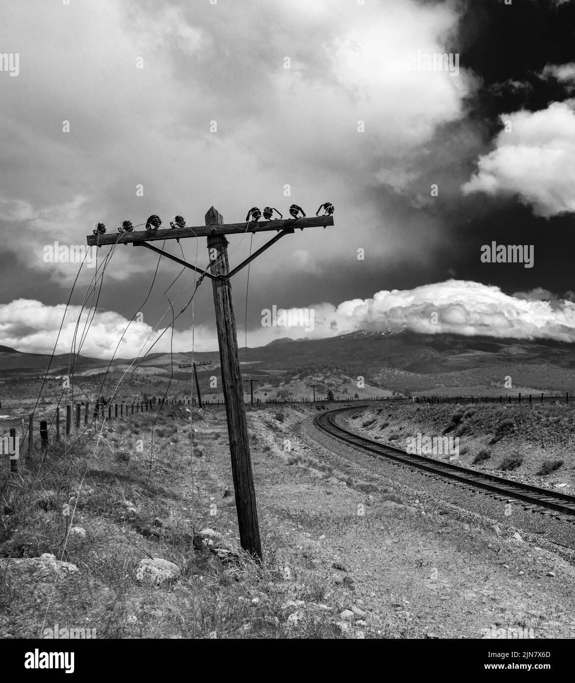 Un colpo verticale di una linea elettrica rotta vicino a una ferrovia in una giornata nuvolosa Foto Stock