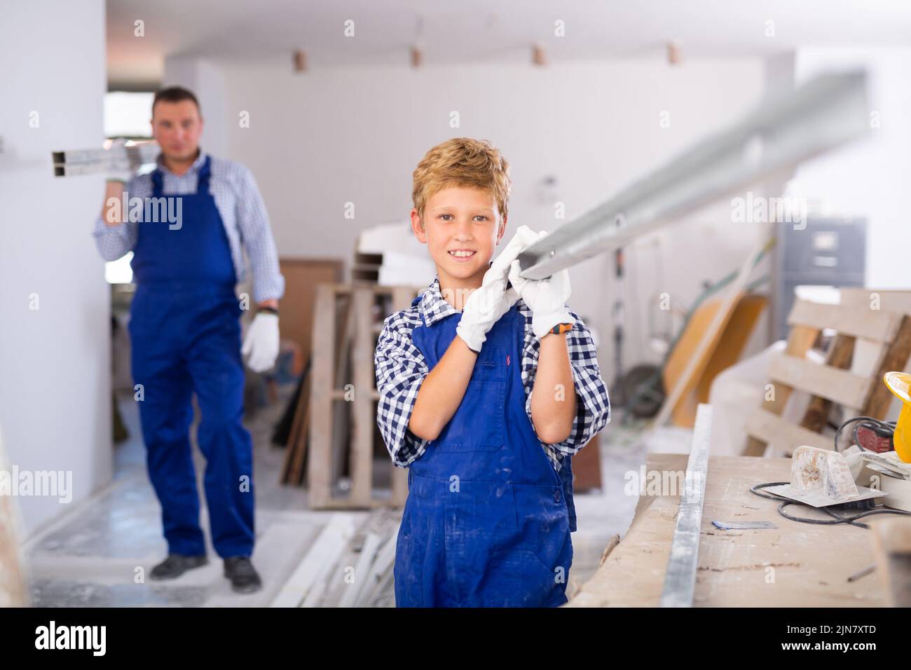 Ragazzo con padre che porta materiali da costruzione Foto Stock