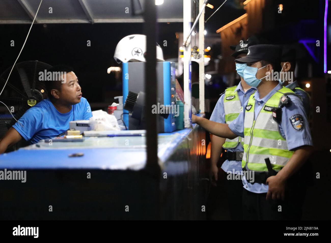 ZHOUSHAN, CINA - 9 AGOSTO 2022 - i poliziotti chiedono informazioni agli operatori di un mercato notturno nella città di Zhoushan, provincia di Zhejiang, Cina, sulla e Foto Stock