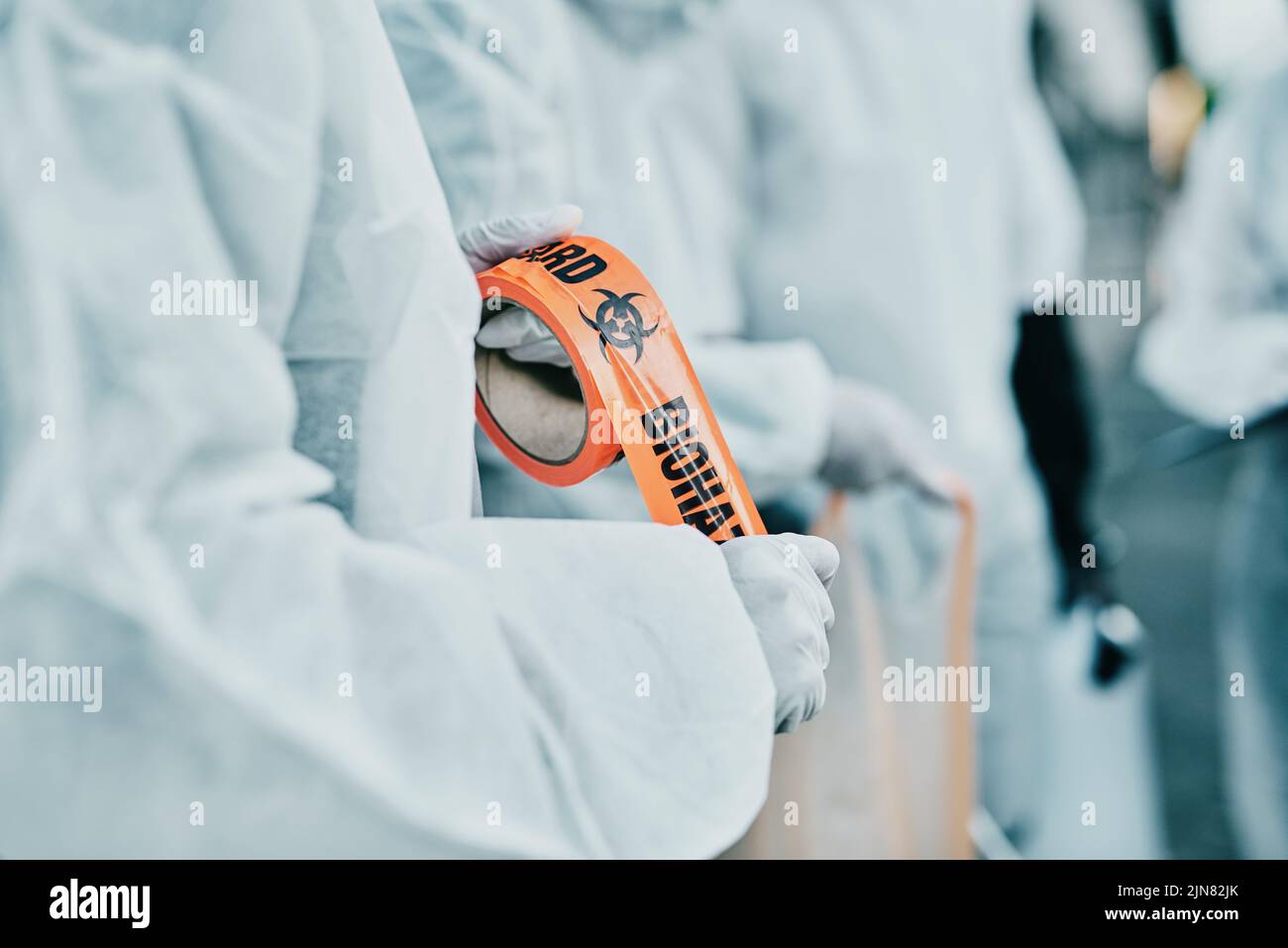 Operatori sanitari di Covid che rispondono a un rischio biologico in un'area pubblica utilizzando nastri di barriera. I soccorritori in tute di protezione hazmat che donano uno spazio Foto Stock