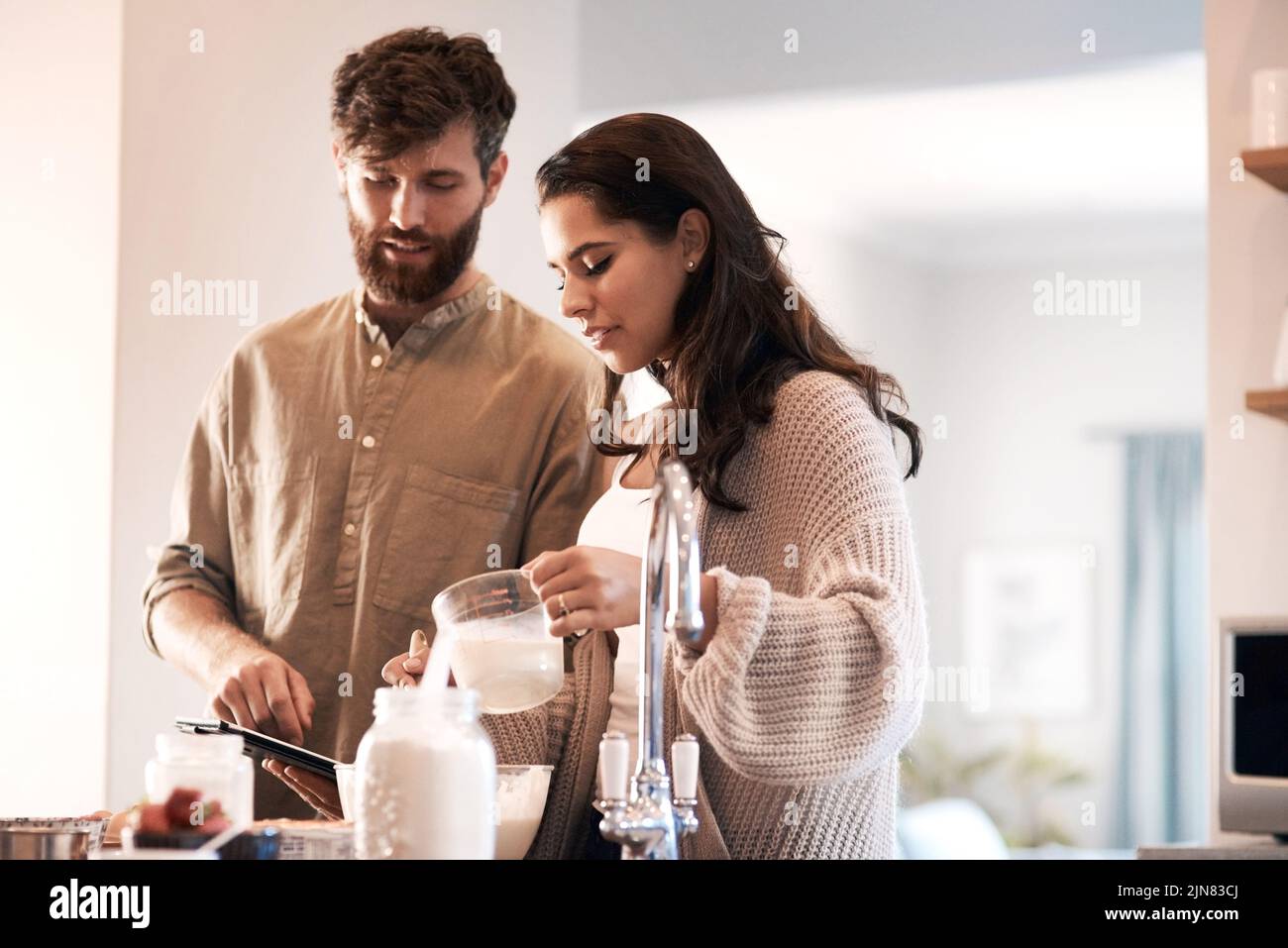 Il lavoro di squadra fa funzionare la pastella. Una giovane coppia prepara la colazione a casa. Foto Stock