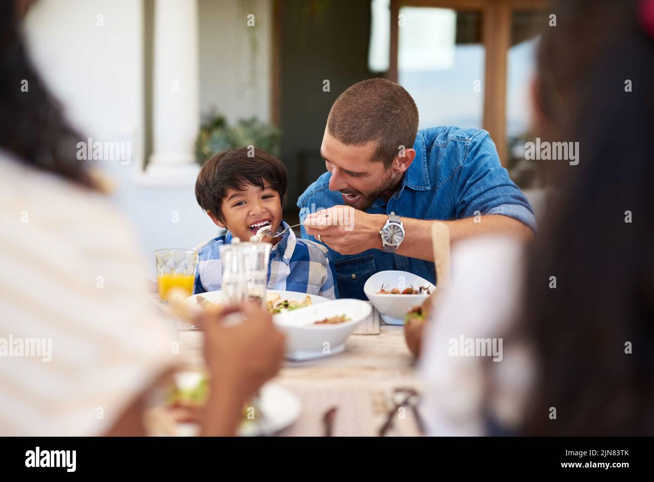 Il suo appetito cresce di giorno in giorno: Un padre che alleva il suo figlio durante un pasto con la famiglia all'aperto. Foto Stock