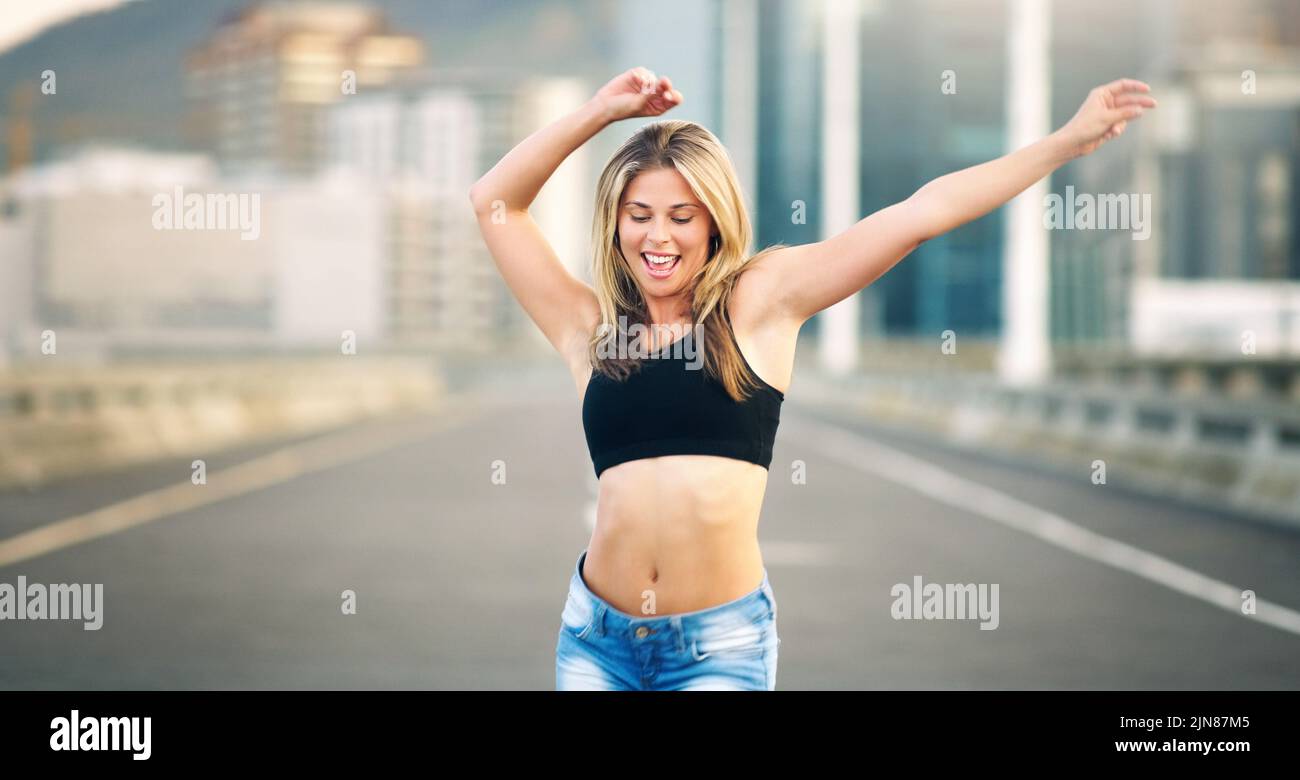 Ballare via tutte le mie preoccupazioni. Una giovane donna attraente che esegue una routine di danza di strada durante il giorno mentre fuori. Foto Stock