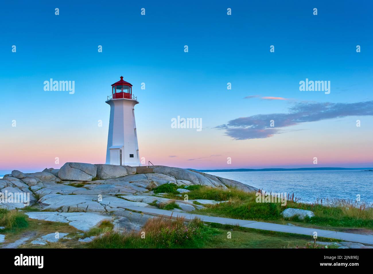 Foto dell'iconico faro di Peggy's Cove scattata all'alba in una bella mattinata estiva. Foto Stock