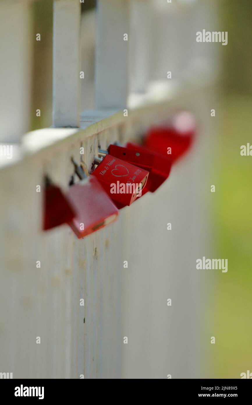 Piccole serrature rosse su recinzione di legno come simbolo dell'amore eterno Foto Stock