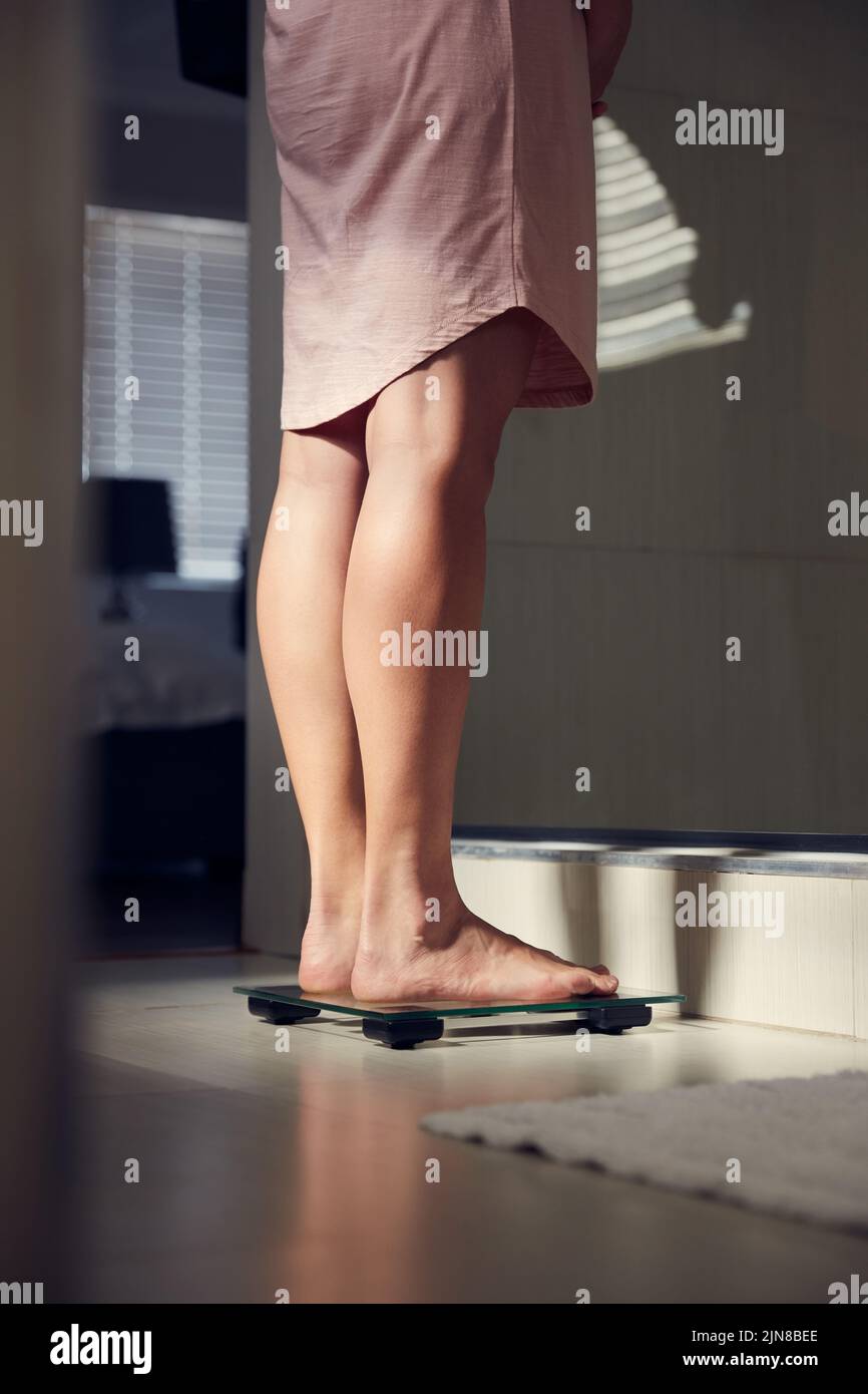 Un progresso lento è meglio di nessun progresso: Una donna inriconoscibile che si pesa su una scala a casa. Foto Stock