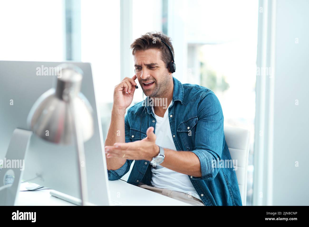 È evidente che è un errore da parte vostra. Un giovane agente del call center che guarda turbato mentre lavora nel suo ufficio. Foto Stock