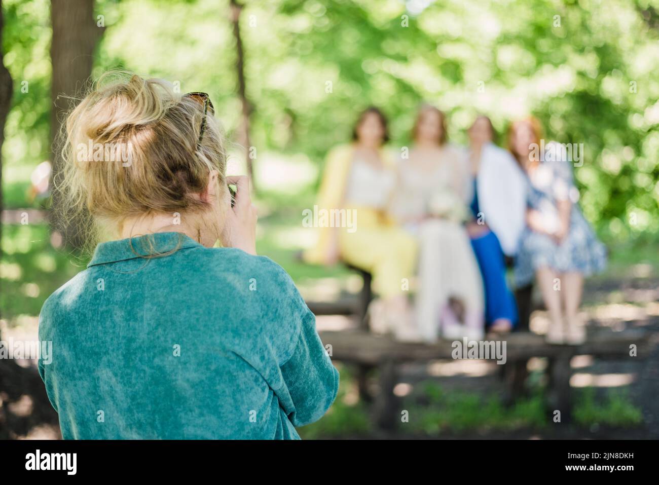 Un fotografo di nozze scatta foto degli ospiti della sposa e dello sposo in natura in una giornata di sole Foto Stock