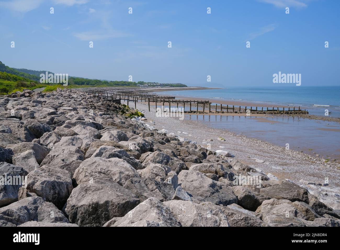 Le rocce costiere di difesa del mare e inguine di legno nella spiaggia di Pensarn nord del Galles Foto Stock