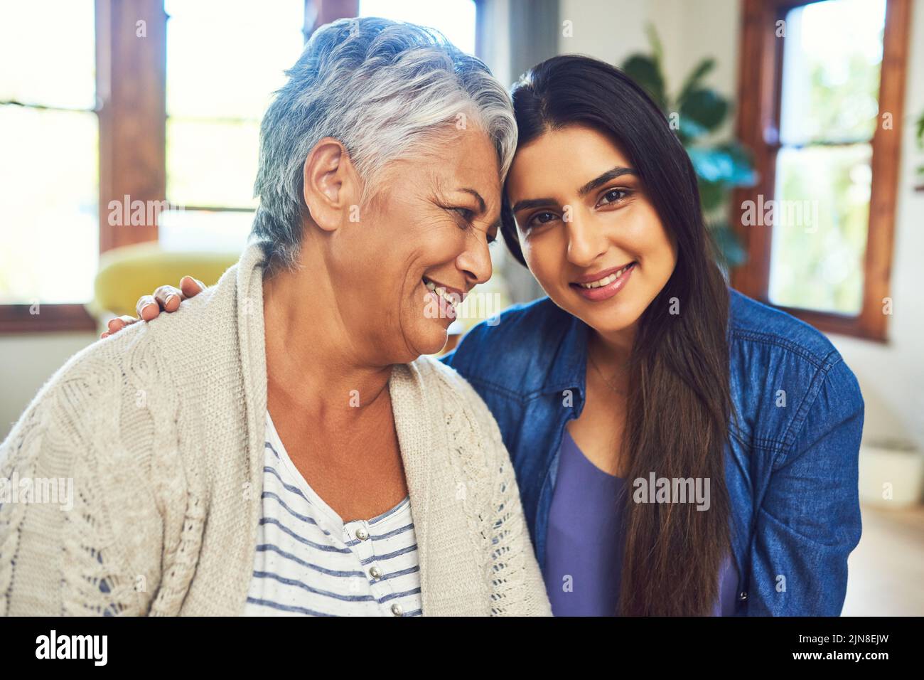 Ammalato sempre fare il tempo per lei. Una bella giovane donna in posa con sua madre mentre si rilassa su un divano a casa. Foto Stock