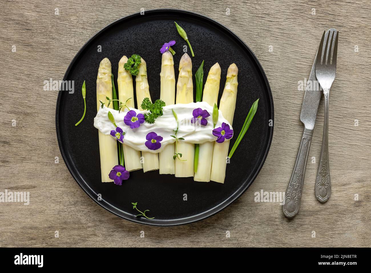 Asparagi bianchi tedeschi con salsa, aglio selvatico e fiori commestibili. Foto Stock
