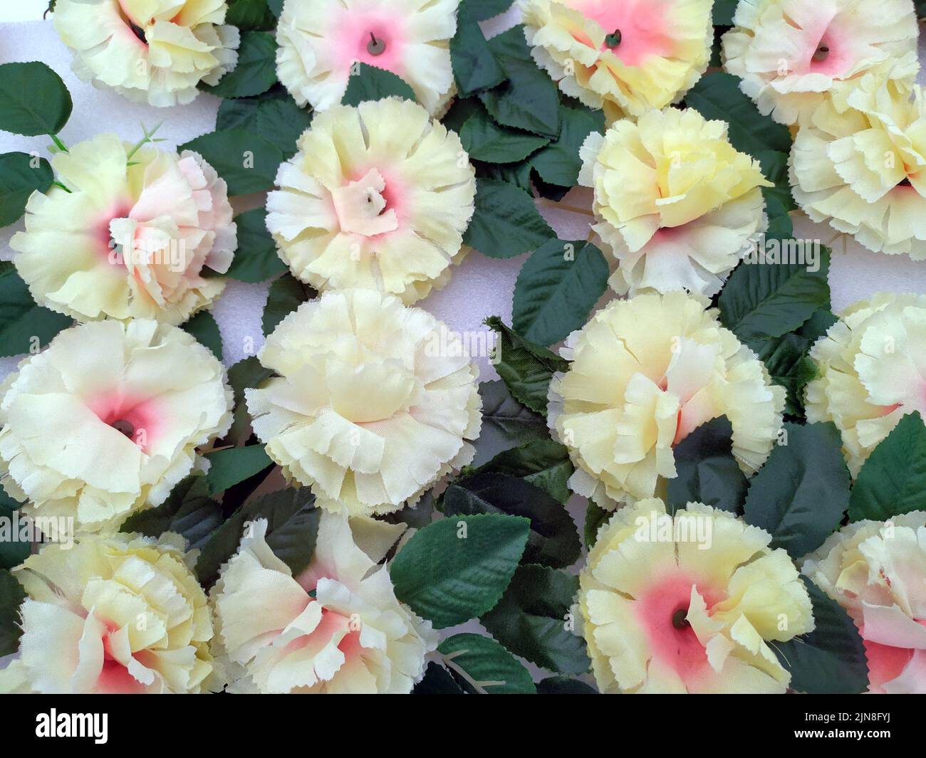 Fiori artificiali di colore giallo chiaro con foglie verdi Foto Stock