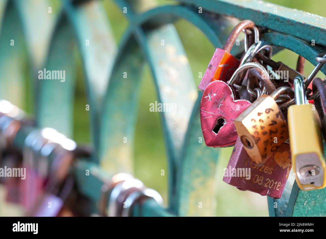 Un primo piano di un cuore e di lucchetti a forma quadrata su un ponte per fare un desiderio d'amore Foto Stock
