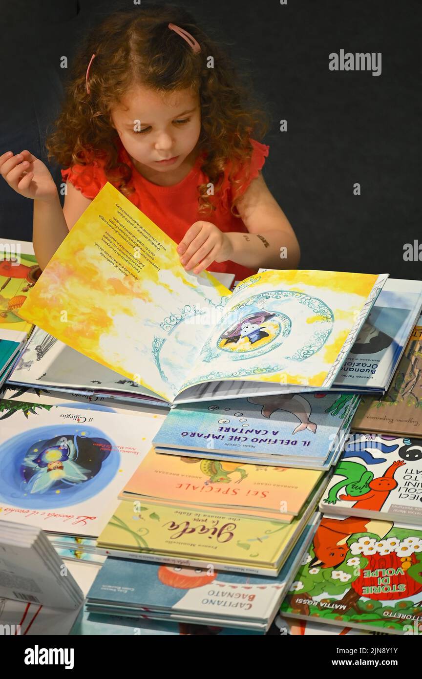Una bambina che sfogliava un libro di storia illustrato alla fiera internazionale del libro Foto Stock