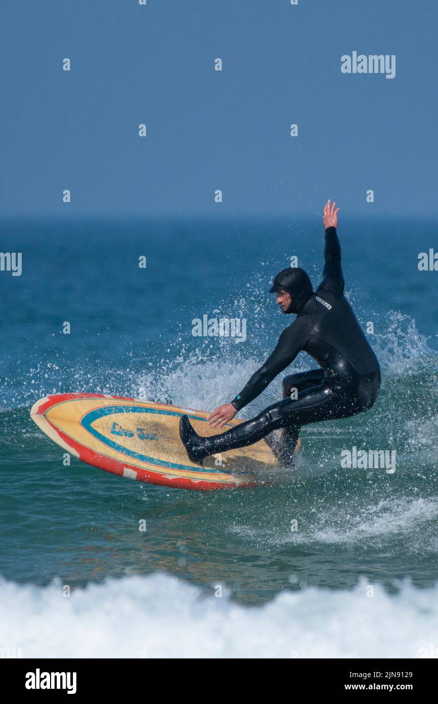 Spettacolare azione di surf come surfista cavalca un'onda a Fistral a Newquay in Cornovaglia nel Regno Unito. Foto Stock