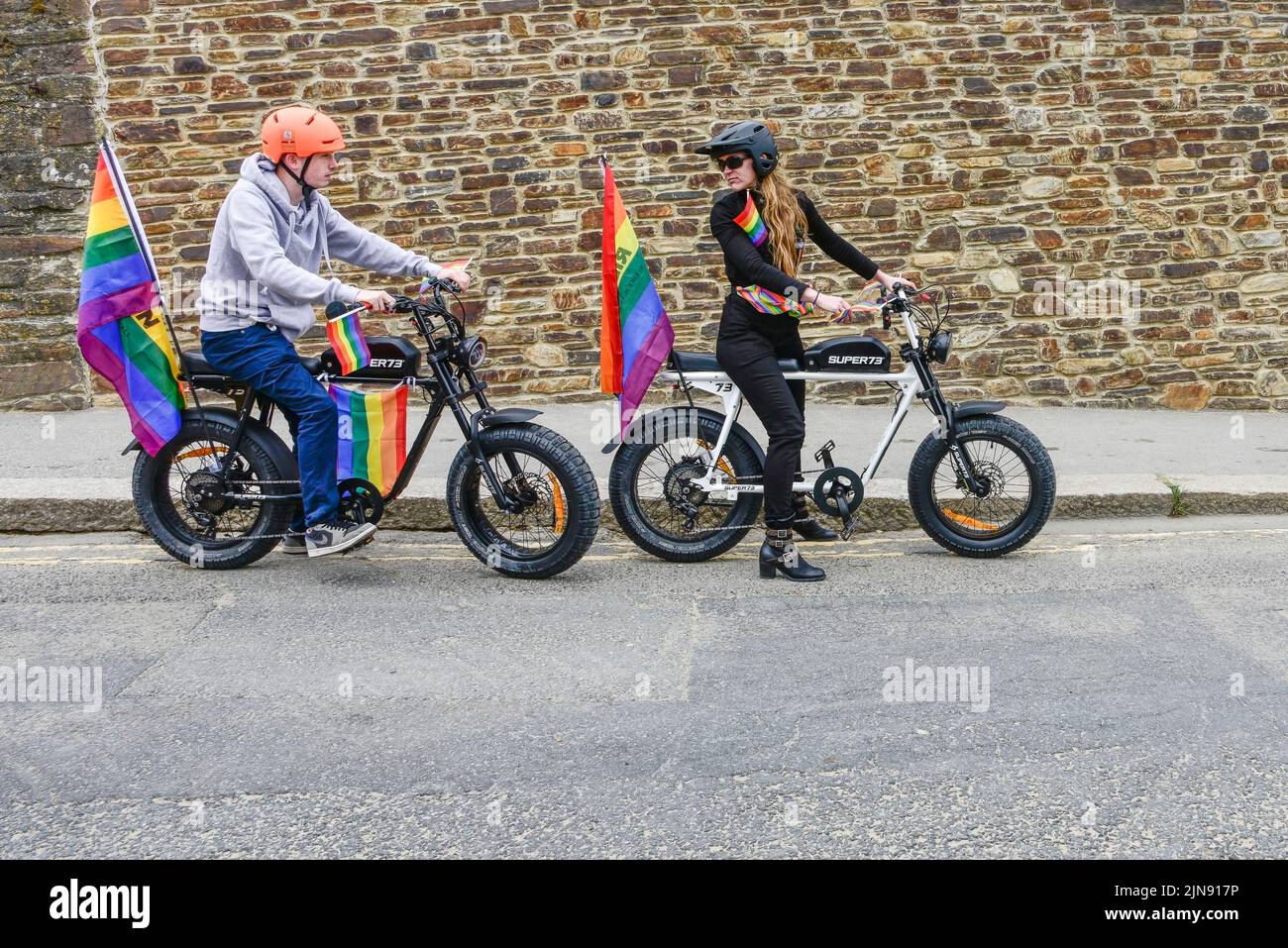 I piloti che usano biciclette elettriche Super 73 all'inizio della vivace e colorata Cornovaglia, sono orgogliosi della sfilata Pride nel centro di Newquay, nel Regno Unito. Foto Stock
